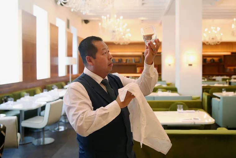 Longtime server Eddie Fong makes sure a glass is spotless while preparing for dinner service at Barclay Prime in Rittenhouse Square. Fong has worked at the restaurant since it opened 15 years ago.