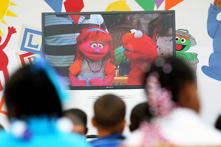 Lily the "Sesame Street" Muppet, pictured left on the TV screen talking with Elmo, is experiencing homelessness with her family to illustrate a growing problem in America.