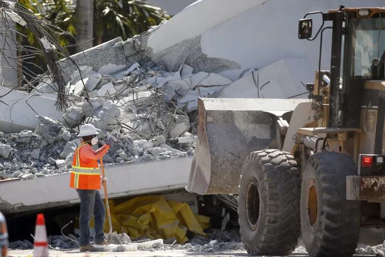 Workers use a front loader to clear debris from a section of a collapsed pedestrian bridge, Friday, March 16, 2018 near Florida International University in the Miami area. The new pedestrian bridge that was under construction collapsed onto a busy Miami highway Thursday afternoon, crushing vehicles beneath massive slabs of concrete and steel, killing and injuring several people, authorities said.