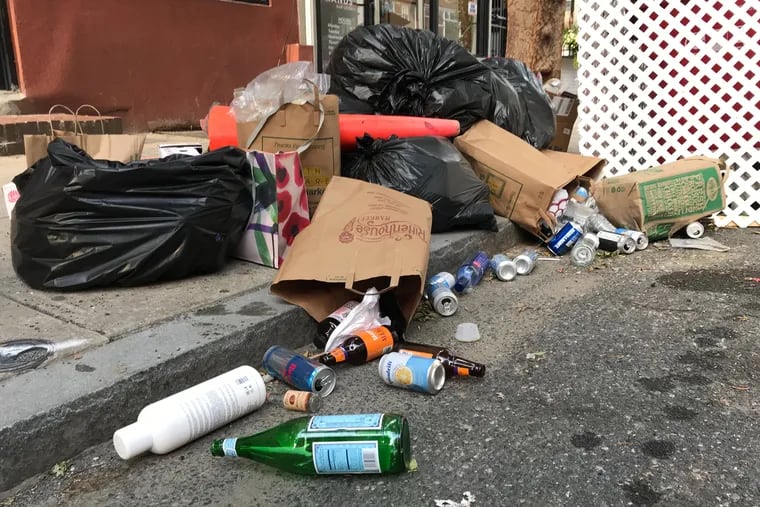 Trash spilling out into the street on South Street between 17th and 18th Streets in Philadelphia on Thursday. Trash and recycling collection has been delayed in Philadelphia because of the impact of COVID-19.