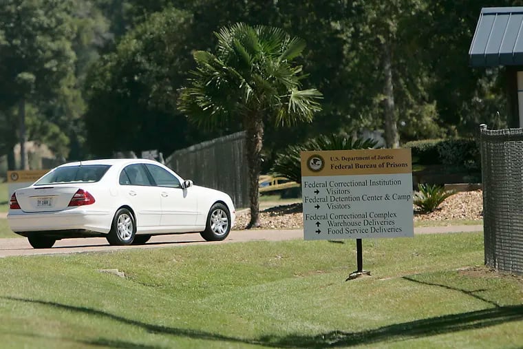 A person drives through the gates of a federal prison in Oakdale, La. The federal Bureau of Prisons is locking all its 146,000 inmates in their cells for the next two weeks in an unparalleled effort to slow the spread of the coronavirus, as the focus shifts to the Louisiana compound, where two inmates have died and nearly 20 others remain hospitalized.