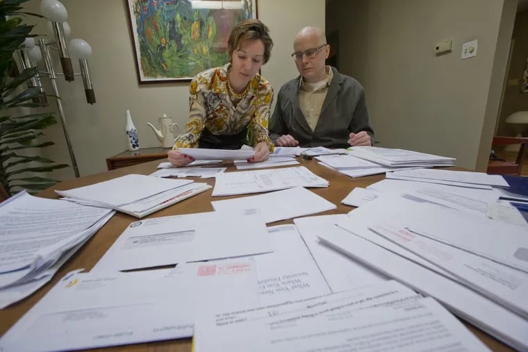 Casey Grabowski (right) and his wife Michelle Dewey go over his medical bills in their North Wilmington, Del., home.