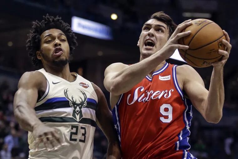 The Bucks' Sterling Brown, left, tries to stop 76ers forward Dario Saric during the first half.
