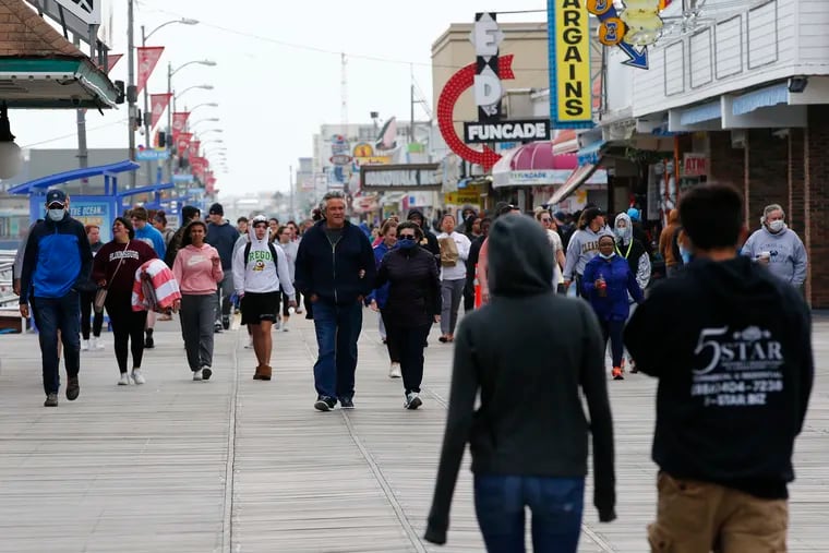 Walkers stroll across the Wildwood Boardwalk in Wildwood, N.J., on Sunday, May 24, 2020, the second day of a slow Memorial Day weekend.