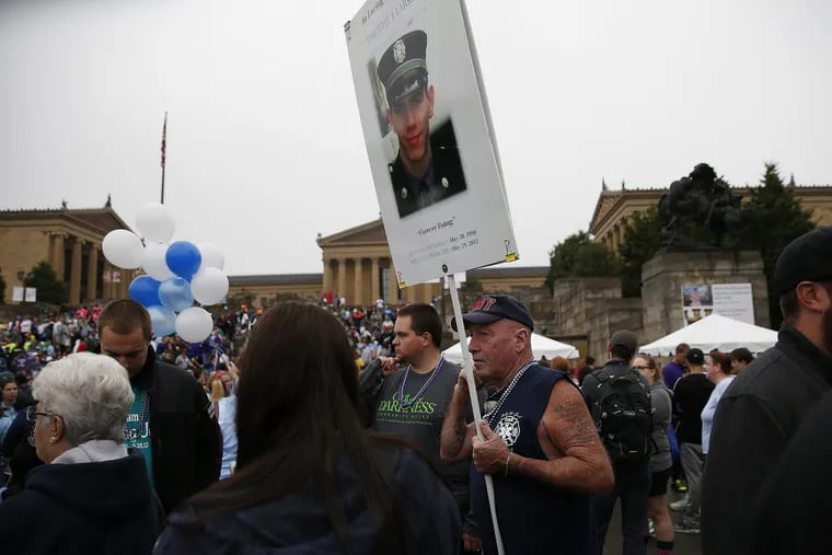 Kevin Larkin, of Downingtown, right, holds up a picture of his son, Timothy, during the American Foundation for Suicide Prevention's 12th Annual Philadelphia Out of the Darkness Community Walk in Philadelphia, PA in  2016.