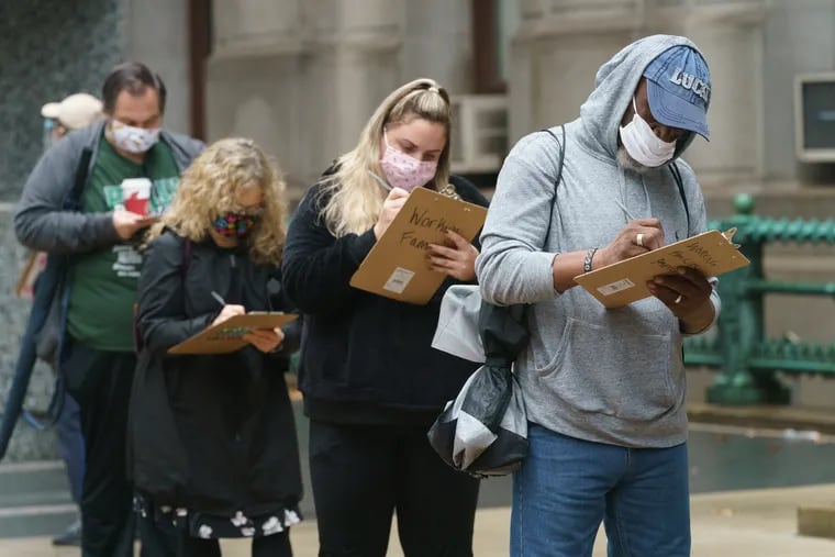 Voters fill out forms while waiting in line to apply for and submit mail ballots at City Hall in Philadelphia on Monday.