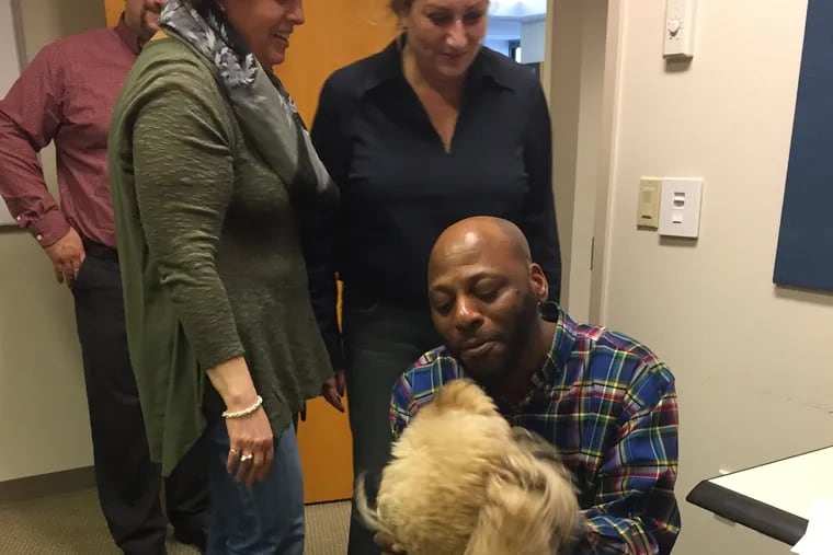 Maggie the goldendoodle spends some quality time with Alonzo Roberts at Isdaner & Co. in Bala Cynwyd. Looking on are Isdaner employees David Lombardo, Rimma Krivitsky and Victoria Zagranichny.