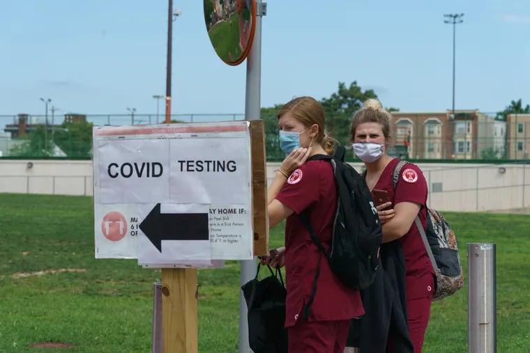 Temple University nursing students Cailee Fodor (left) and Kelli Snyder wait at the COVID-19 testing site on campus, where classes started Monday.