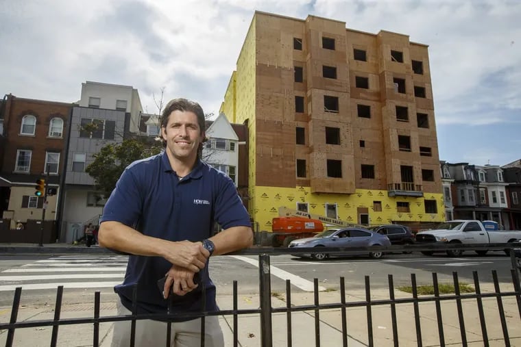 Developer Gary Jonas stands at the corner of 42nd Street and Chestnut where an apartment complex, background, he is building in under construction.