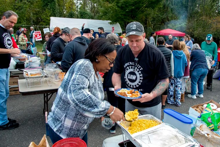 Robin Pinkney (left) serves mac n' cheese for Robert Tancredi (right) both union members of United Auto Workers Local 2177, at the picket line outside the General Motors parts distribution center in Langhorne on the evening of Sunday, October 13, 2019.  Union members and supporters from the community brought food for a potluck supper in support of the over 70 members of Local 2177 on strike since Sept. 16 as part of a nationwide walkout against the company.