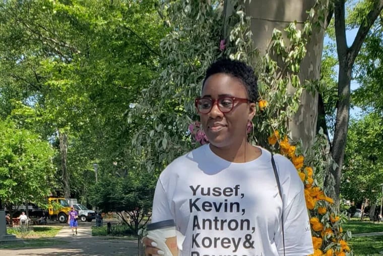 Writer Queen Muse, pictured in Clark Park wearing a shirt honoring the "Central Park Five" teenagers wrongfully convicted for an assault that occurred in 1989 in New York City, recently became the only Black woman journalist at a publication she works for.