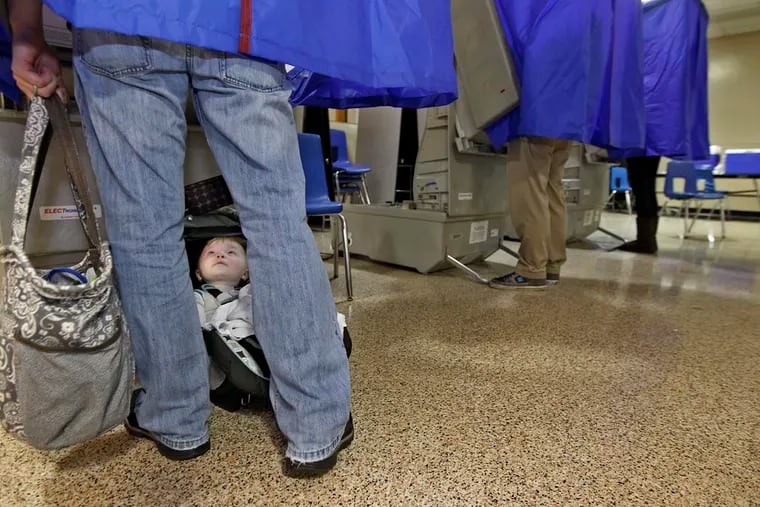 Jack Holder, 9 months old, looks up at his father, Brian Holder of Bensalem, as he casts his vote at the polls located in the cafeteria of Bensalem High School in November 2013.
