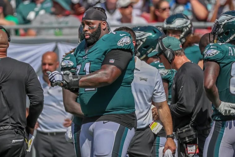 Jason Peters, injured on the sidelines, uses hand signals to communicate with his sub, Halapoulivaati Vaitai, in the third quarter.