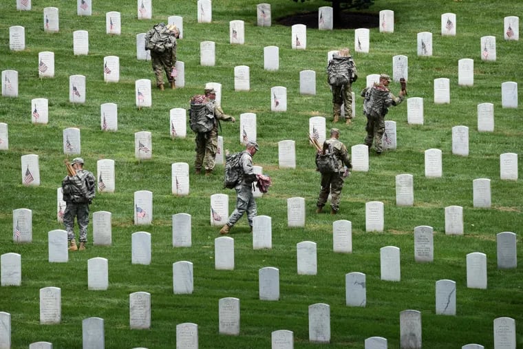 Soldiers from the 3rd U.S. Infantry Regiment place flags at grave sites in Arlington National Cemetery on May 25.