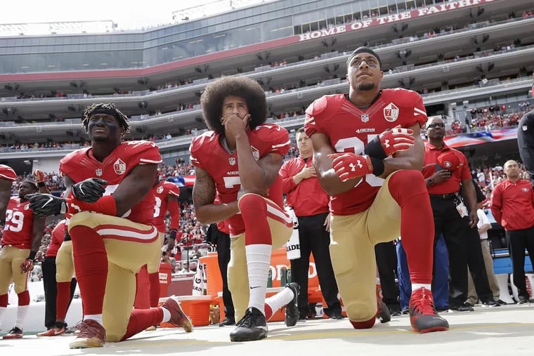 Colin Kaepernick (center) kneeling in 2016 during the national anthem