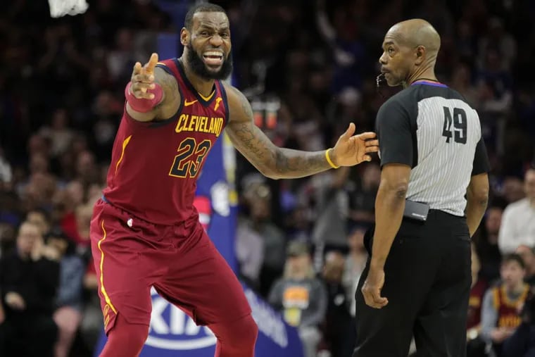 LeBron James (left) disputes a call with official Tom Washington during the Sixers’ win over the Cavs on Friday.