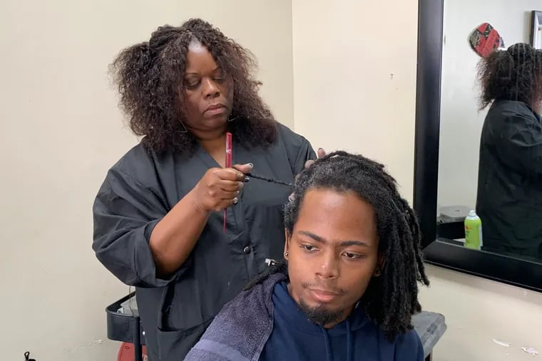 Charlotte "Peaches" Smith, owner of the Dreadlocks Salon in Oakland, Calif., works on a customer's dreadlocks. California was the first state to ban workplace and school discrimination against Black people for wearing hairstyles such as braids, twists, and locs.