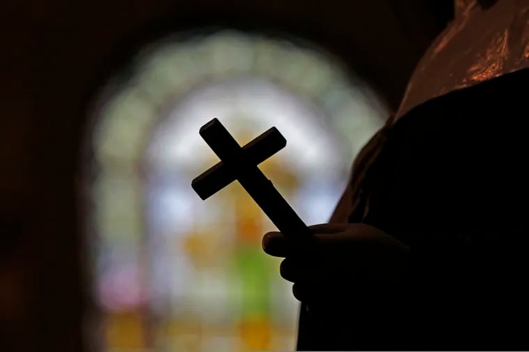 FILE - This Dec. 1, 2012 file photo shows a silhouette of a crucifix and a stained glass window inside a Catholic Church in New Orleans.
