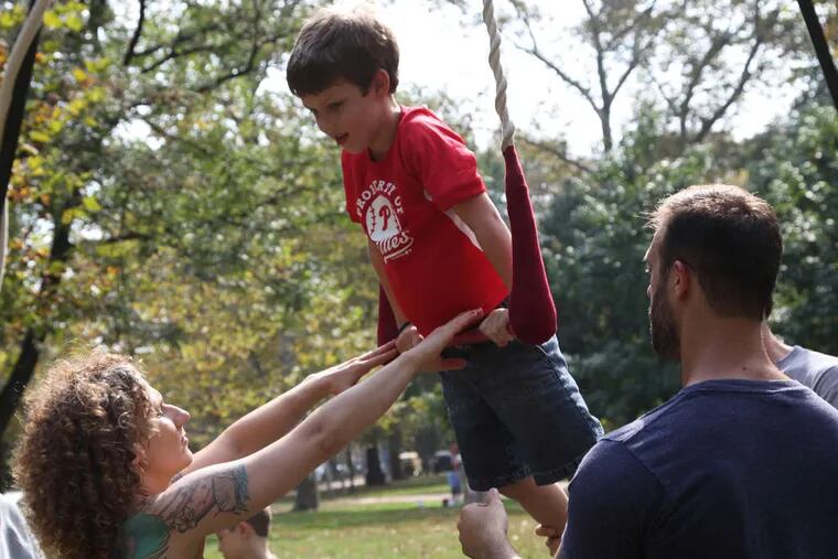 Cole McIntosh, 6, enjoys learning the trapeze from Erin Flanigan and Nick O'Kane of the Cotton Candy Circus during the city's first Figment festival at Clark Park in West Philadelphia.
