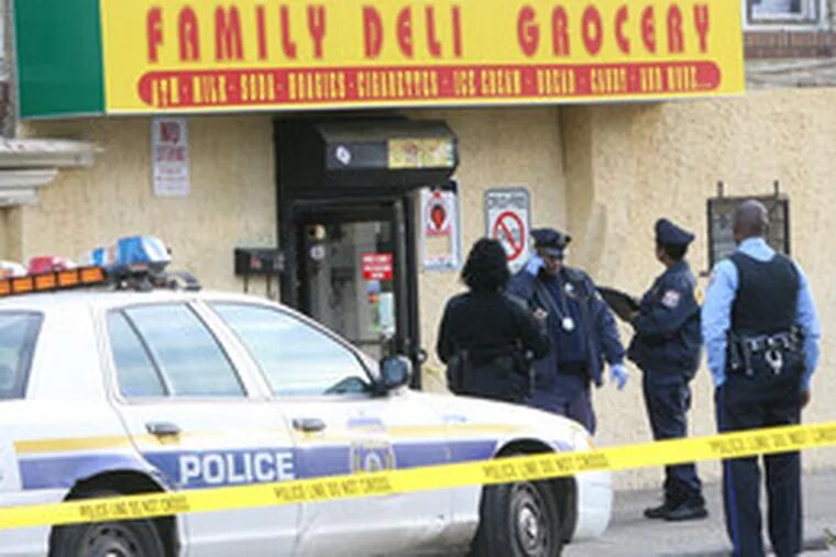 Cops investigate a crime scene on Cornelius Street in Germantown yesterday. A grocery-store clerk, identified as a 20-year-old woman, was shot dead.