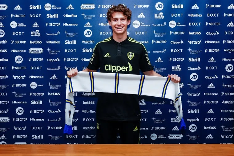 Brenden Aaronson holds up a Leeds United scarf after the Medford native and former Union player signed with the English Premier League team.