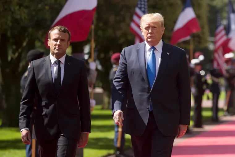 U.S President Donald Trump and French President Emmanuel Macron, right, attend a ceremony to mark the 75th anniversary of D-Day at the Normandy American Cemetery in Colleville-sur-Mer, Normandy, France, Thursday, June 6, 2019. World leaders are gathered Thursday in France to mark the 75th anniversary of the D-Day landings. Man at left is unidentified. (Ian Langsdon/POOL via AP)