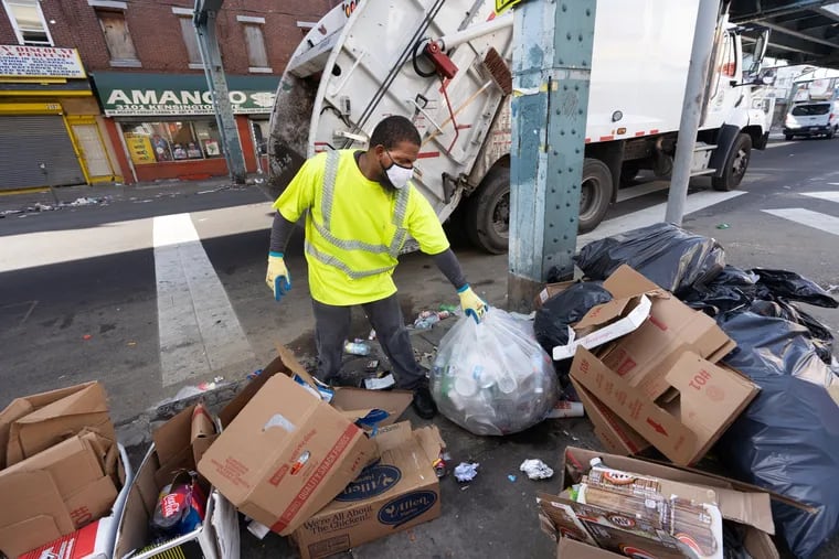 Sanitation worker Rashan Purcell collects trash on Kensington Avenue on July 27.