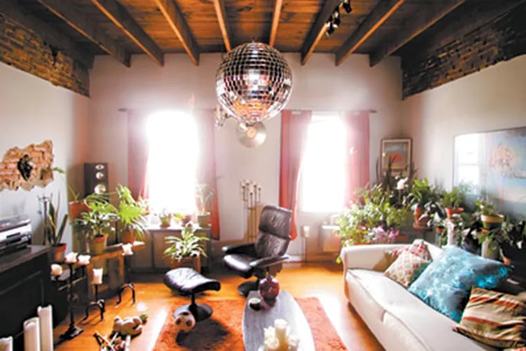 Sunlight pours into the house, and the disco ball hanging from the exposed beams of the living room ceiling delights party guests. (David Swanson / Staff Photographer)