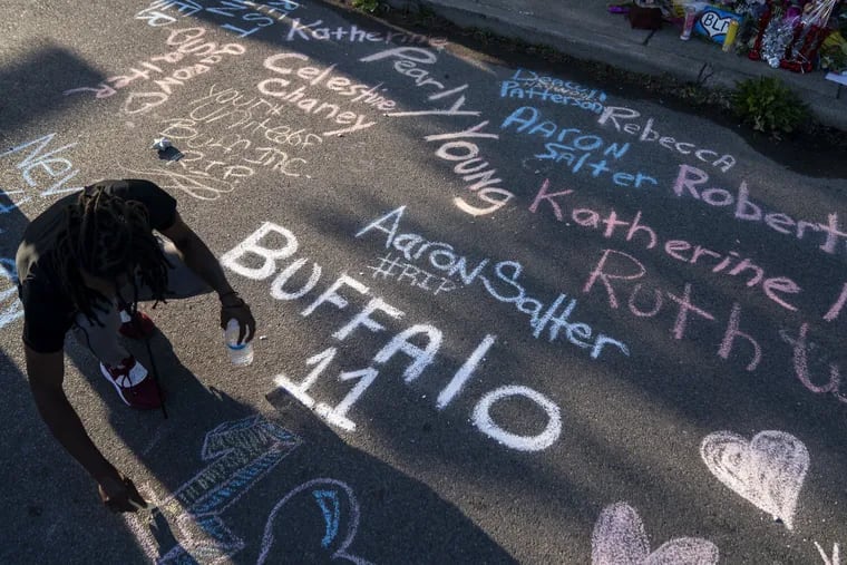 Aaron Jordan adds to a sidewalk chalk mural depicting the names of the people killed in a mass shooting at a Tops Friendly Market in Buffalo, N.Y., on Sunday.