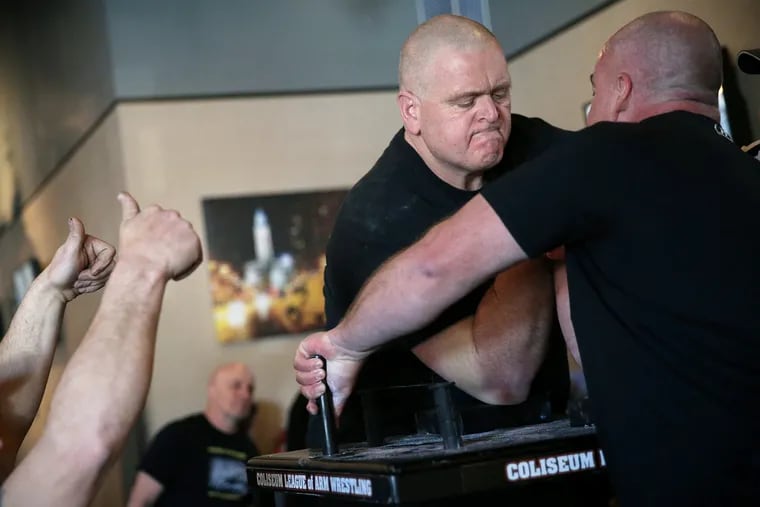 Steve "The Animal" Walker (rear) faces off against Philadelphia police officer Brian Cain at the Winter Slam arm wrestling tournament at the FOP.