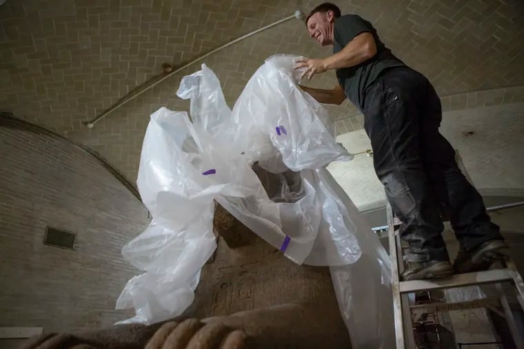 Eric Schultz uncovers the granite sphinx at the Penn Museum prior to Wednesday's planned journey from one part of the Penn Museum to another. Schultz is part of the team that will be moving the sphinx.