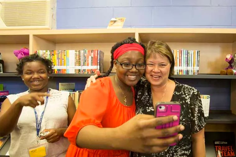 Friday June 6, 2014, At Mastery Charter School in West Philadelphia family, friends, teachers and students came together to honor teacher Jamie Soukop Reid who was killed in a North Carolina car crash last year.As they dedicated a new library in her honor both tears and smiles were present in the room. Here, Jamie's mom Kay poses for a selfie with student Massandje Dosso, 13, as classmate Shadiyah Marable, 14, left looks on.(ED HILLE / Staff Photographer )