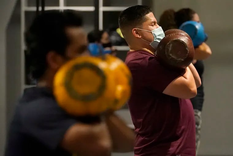Juan Avellan, center, and others wear masks while working out in an indoor class at a Hit Fit SF gym amid the coronavirus outbreak in San Francisco.