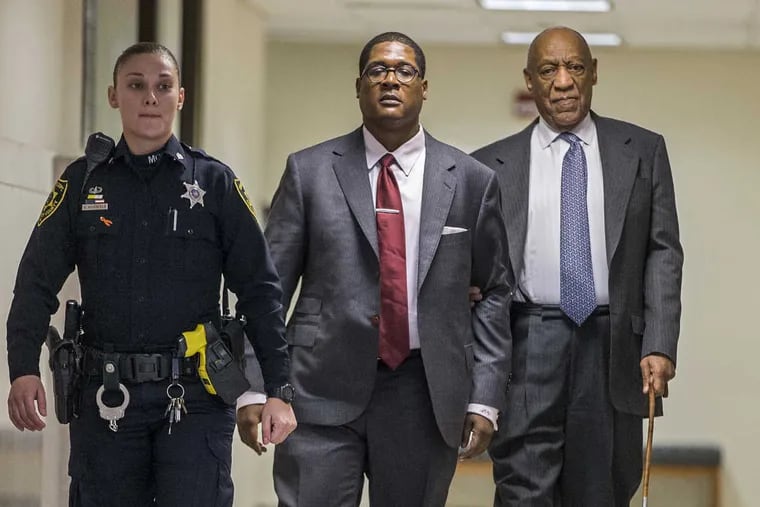Bill Cosby (right) holds onto Andrew Wyatt as they are escorted by an officer of the Montgomery County sheriff out of Courtroom C, for a short break, at the Montgomery County Courthouse on the second day of jury selection in his sexual assault retrial April 3, 2018, in Norristown, Pa.