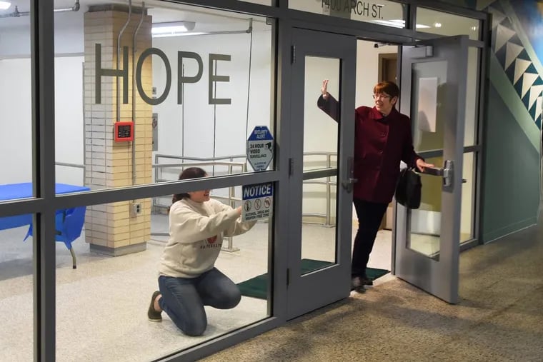 Project HOME president and executive director Mary Scullion (right) says good night as hospitality coordinator Emily Hopkins (left) finishes up applying signage in the subway concourse entrance to the soon-to-open “Hub of Hope.”