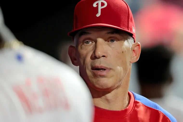 Phillies manager Joe Girardi talks with pitcher Hector Neris in the dugout during  a game against the Cubs  on Sept. 15.
