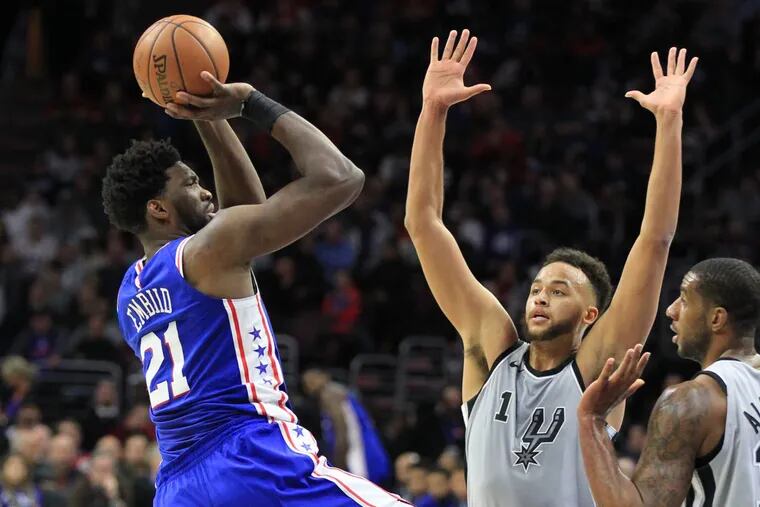 Joel Embiid, left, of the Sixers shoots over Kyle Anderson, center, and LaMarcus Aldridge of the Spurs during the 2nd quarter at the Wells Fargo Center on Jan 3, 2018. Embiid is playing with an injured hand.
