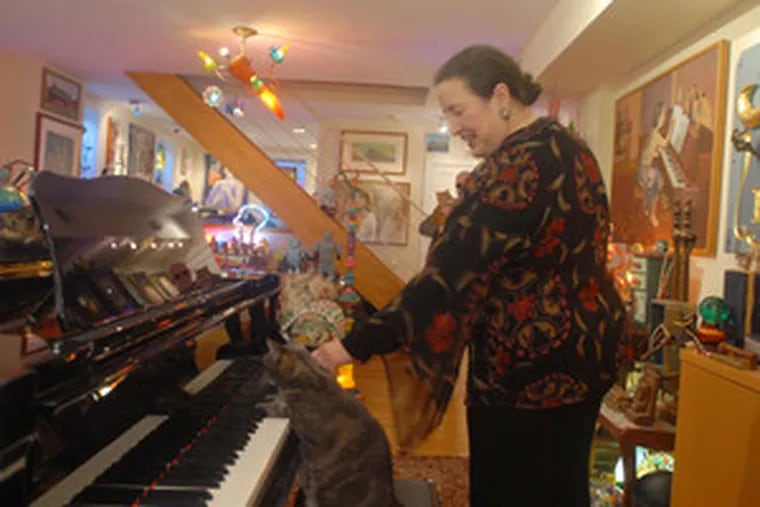 Betsy Alexander, owner of Nora, the piano-playing cat, in her Center City studio. Nora plays along with Alexander&#0039;s students in their lessons.