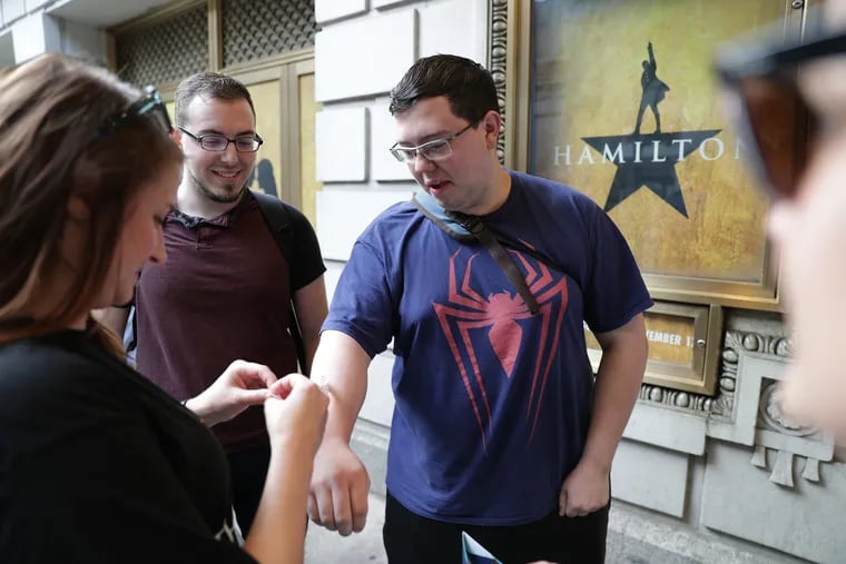 Mike Bradley, right, 26, of Northeast Philadelphia, was the first in line Tuesday to receive a wristband to purchase Hamilton tickets on the first sale date. He arrived at midnight with his friend, Howard Stickley, 24, at left. As of Wednesday afternoon, tickets were still available, no wristband required.