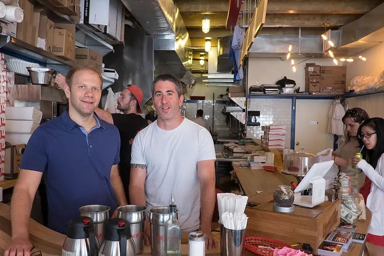 Federal Donuts co-owners Steve Cook, left, and Mike Solomonov behind the counter at their Sansom Street store. The restaurant partnered with Broad Street Ministry and ran a Kickstarter campaign to raise funds to open Rooster Soup Co. Proceeds from the soup company will go to Broad Street Ministry, which works with the city's homeless and hungry.