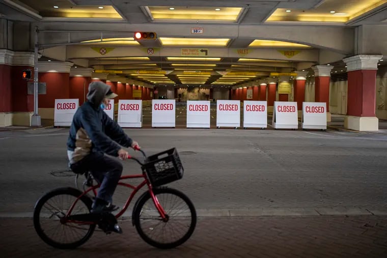 A person rides their bike by the Tropicana Atlantic City Hotel has road blocks reading “Closed” to prevent drivers and people from entering the hotel in Atlantic City, N.J.,