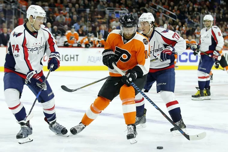 Flyers center Sean Couturier skates with the puck against Washington defenseman John Carlson (left) and right winger T.J. Oshie. Carlson, who had a mega-season and helped the Caps win the Stanley Cup, was selected by Washington with a first-round pick acquired from the Flyers in 2008. 