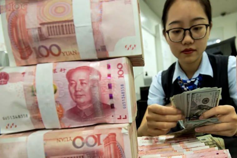 A bank employee counts U.S. dollar banknotes next to stack of 100 Chinese yuan notes at a bank outlet in Hai'an in eastern China's Jiangsu province on Tuesday.