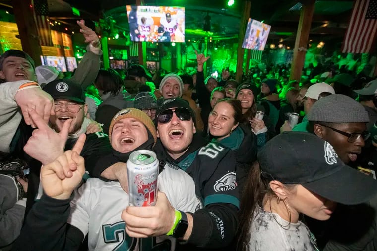 With dejected 49er players on the TV screen, Eagle fans celebrate in the final minutes of the game at Xfinity Live. The Eagles won the NFC Championship Game against the San Francisco Forty-Niners on Jan. 29, 2023. Just how far would Eagles fans go for a Super Bowl win?
