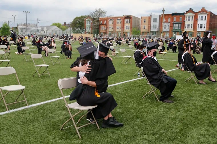 Temple University graduates Justin Brown (right) and Zamira Chevrestt embrace during the College of Liberal Arts commencement on Geasey Field at the Temple University campus in North Philadelphia on Friday, May 7, 2021.  The College of Liberal Arts is the first in-person commencement since pandemic.  .