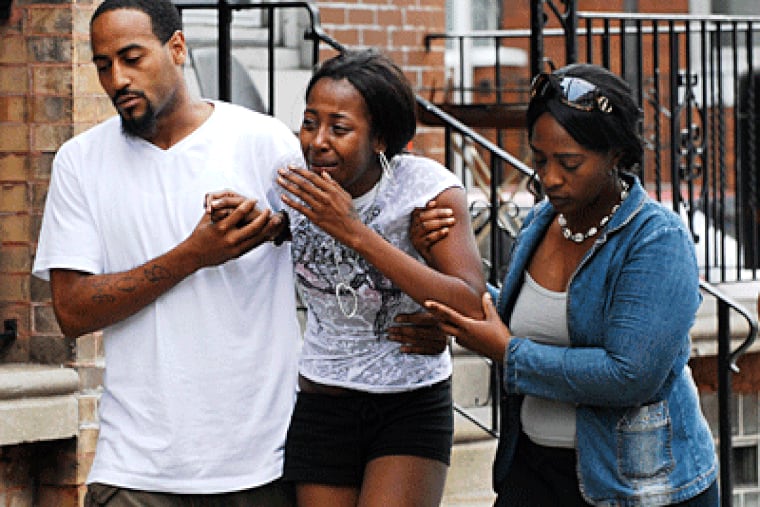 A woman identified by a neighbor as the girlfriend of the shooting victim is escorted to the scene, on North Chadwick Street in the Logan section of Philadelphia. (Sarah Glover / Inquirer)