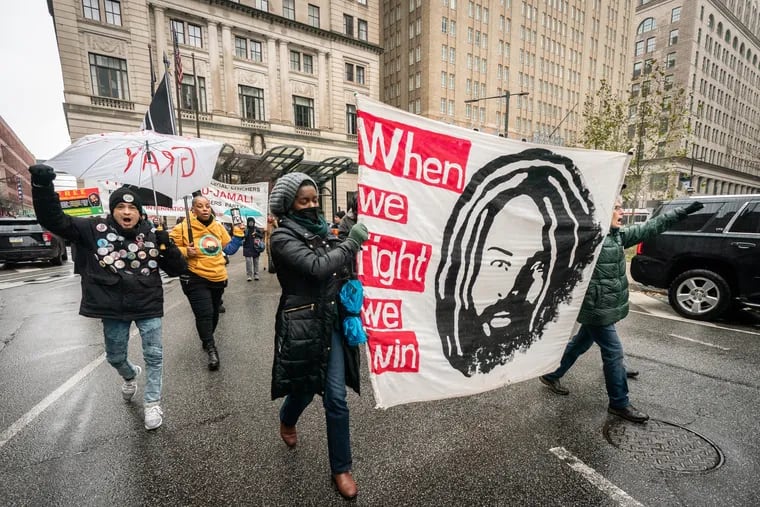 Supporters of Mumia Abu-Jamal march down JFK Blvd. past the Juanita Kidd Stout Center for Criminal Justice and City Hall, in Philadelphia, Friday, December 16, 2022.