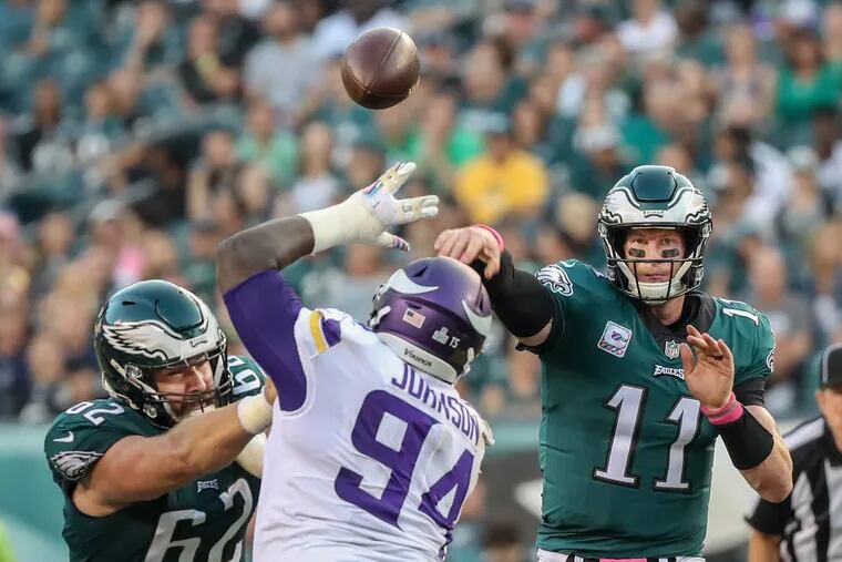 Jason Kelce (left) does his best to keep the Vikings' Jaleel Johnson away from Eagles quarterback Carson Wentz.