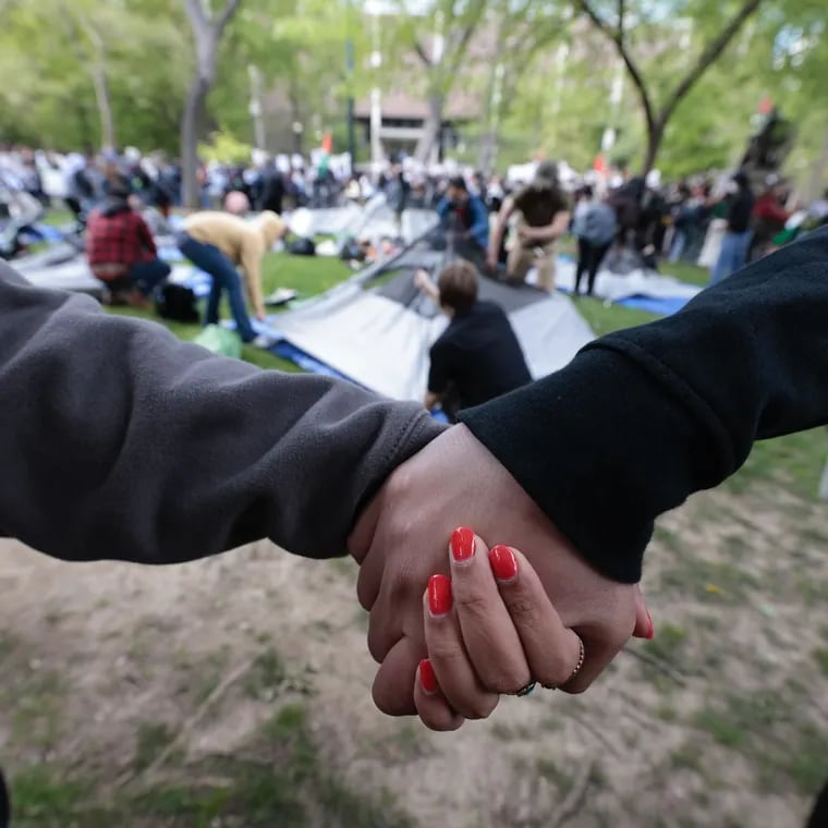People join hands in a circle as tents are erected on Penn’s campus as part of a pro-Palestinean protest in Philadelphia on Thursday, April 25, 2024.