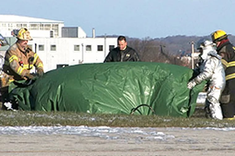 Workers cover the body of a man killed in the crash at New Castle Airport.